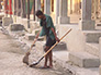 A woman cleans in front of her home
