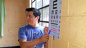 A volunteer points to the eye chart during a screening